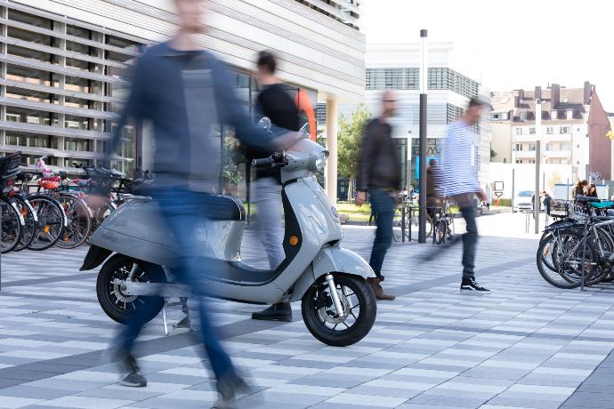 man in black suit riding on blue motor scooter